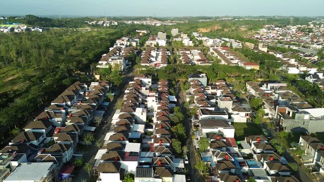 Aerial drone shot of a modern suburban residential housing complex with uniform architectural design surrounded by lush green trees and natural