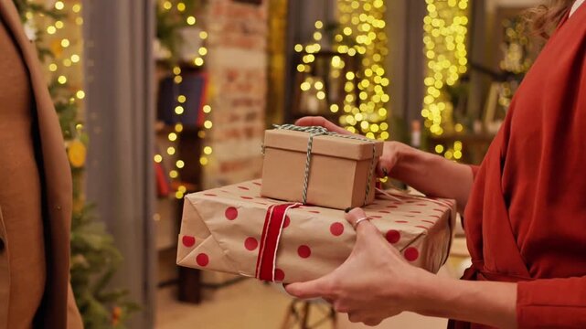 Close-up of a Man and Woman Exchanging Wrapped Gifts in a Warmly Lit Festive Home Interior