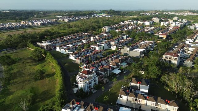 High angle aerial view of a modern residential housing complex in a suburban area with green landscapes and organized infrastructure under a clear