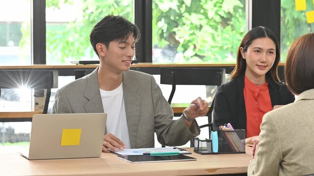 Female Job Candidate Speaking During Panel Interview with Smiling HR Recruiters in Modern Office