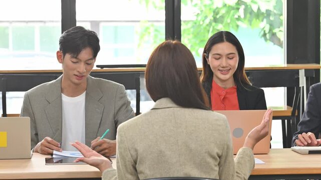 Female Job Candidate Speaking During Panel Interview with Smiling HR Recruiters in Modern Office