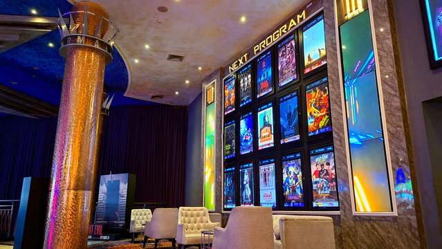 Modern movie theater lobby interior with illuminated digital next program poster display screens and luxury armchair seating area on September 28, 2026 in Bangkok, Thailand.