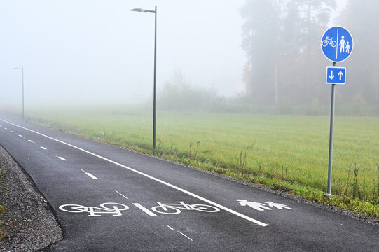 An asphalt bicycle and pedestrian path on a foggy autumn morning in Finland