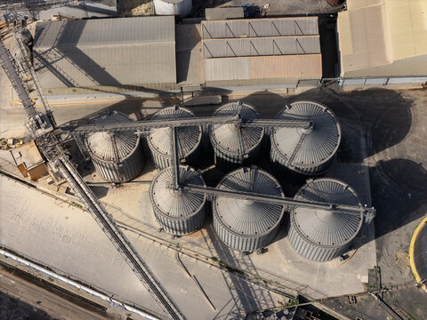Aerial view of industrial grain silos in an industrial facility with metal structures and paved ground in Bajos de Haina, San Cristobal Provinc, Dominican Republic.
