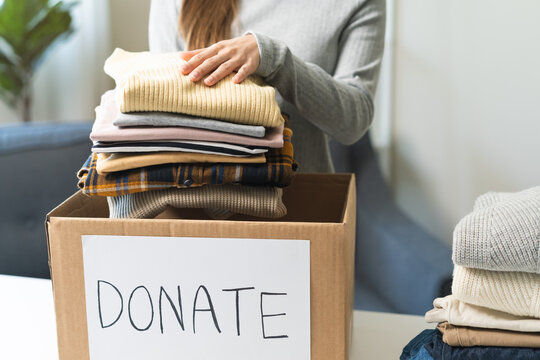 Recycling, Donation for poor, asian young woman, girl pack object at home, putting on stuff into donate box with second hand clothes, charity helping and needy people. Reuse recycle, moving.