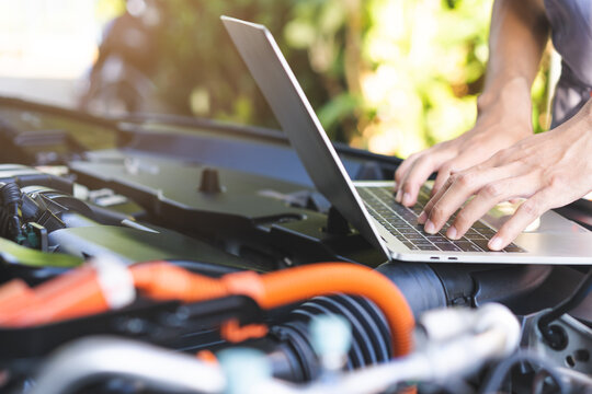 Professional car mechanic hands using laptop computer for diagnostic checking system and vehicle performance analysis during engine service maintenance in auto repair workshop garage.
