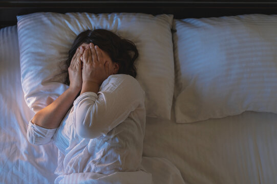 Sleep deprivation, insomnia, difficulty waking up in the morning; a woman in bed on pillows.