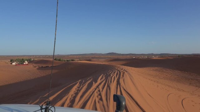 First-person view of an off-road safari driving on the sand dunes of the desert, showing an extreme adventure tour with a 4x4 car under a clear blue sunny sky