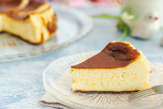 A slice of Basque burnt cheesecake on a glass plate with a fork.