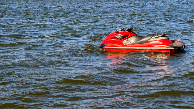 Red personal watercraft floating idly on blue water, symbolizing water sports, summer fun, and an adventurous outdoor lifestyle during a relaxing vacation or holiday