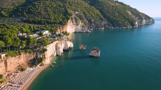 Baia delle Zagare Gargano Puglia Italy 4K drone video. Faraglioni sea stacks pink sunrise over white cliff beach luxury resort. Travel b roll stock footage