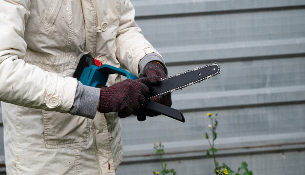 Person uses chainsaw for garden work in autumn