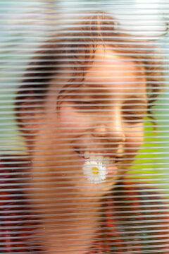 Girl Smiling Behind Transparent Material With a Flower