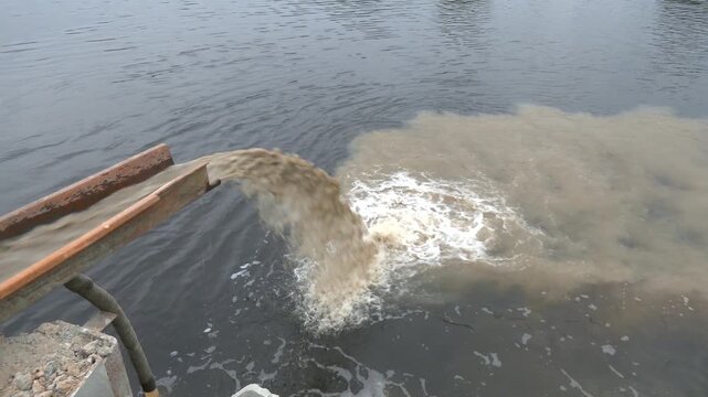 Pollution of the environment by industrial outfalls. Flow of dirty water flows out of the pipe.  Dirty sewage pollutes the environment. Powerful waste stream from the pipe