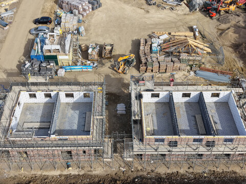 Interesting drone UAV view of partially completed semi-detached new build homes seen on a new housing development site in Britain. Both private and affordable homes will be available for sale.