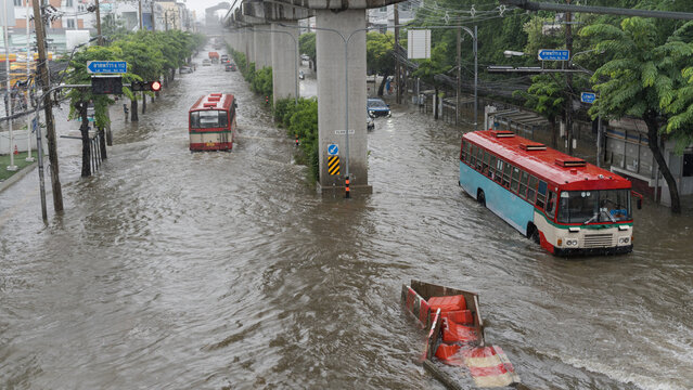 Urban street flooding with public buses navigating through deep rainwater on the road