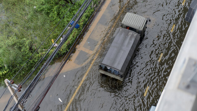 A military truck drives through a flooded city street during a heavy rainstorm from above view