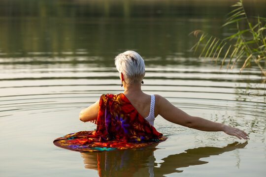 An older woman enjoys the calm water in evening light