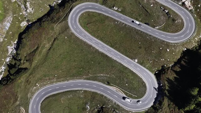 Aerial view of the winding Julier Pass road leading towards Silvaplana with cars driving through the alpine landscape in Surses, Grisons, Switzerland.