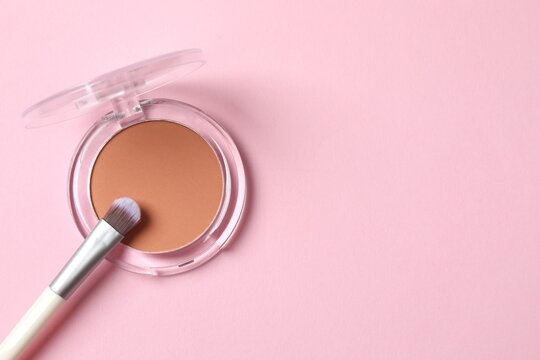 Make-up powder with brush on pink background