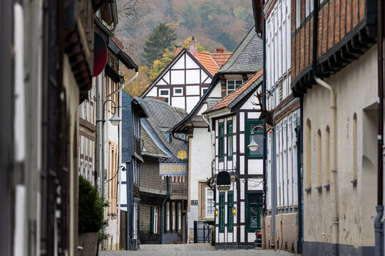 Scenic Goslar rooftops frame historic street with half timbered houses, slate facades and museum sign. Soft autumn tones and hazy hills create tranquil heritage mood in charming old town center