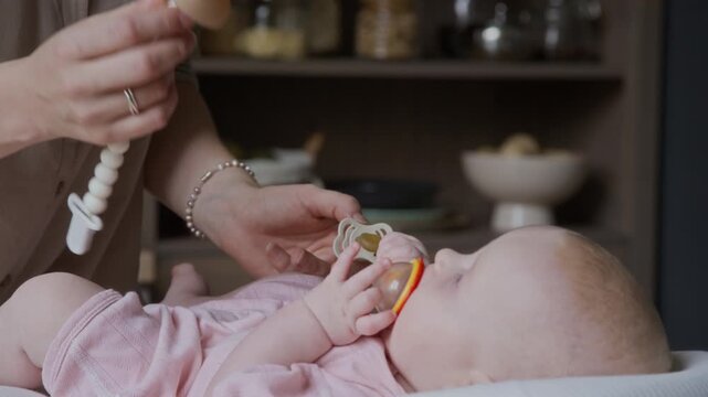 Caucasian mother offering pacifier to newborn baby lying down, camera tilting up to her face. Perfect footage for baby care branding, parenting commercials, maternal health campaigns