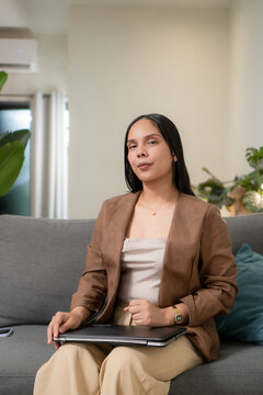 Young adult woman holding computer at home
