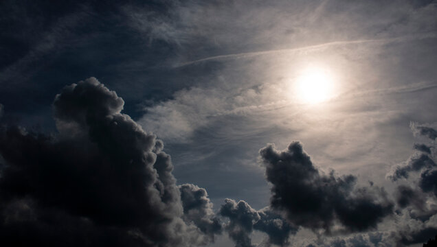 Parte superior derecha aparece un sol muy brillante, parcialmente rodeado por nubes finas y luminosas.