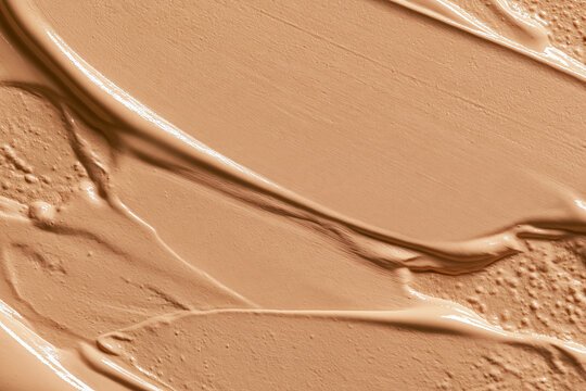 Beige liquid foundation smear texture with cosmetic cream strokes and abstract patterns for skin tone beauty product background