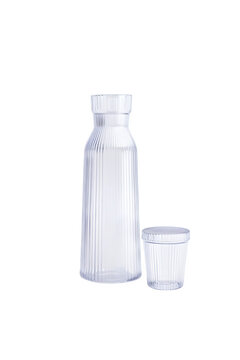 Ribbed glass carafe and matching small drinking cup presented as elegant kitchenware on transparent background