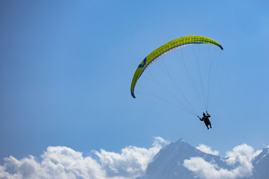 View of a paraglider soaring through the clear blue sky above the mountains of Booni, Khyber Pakhtunkhwa, Pakistan.