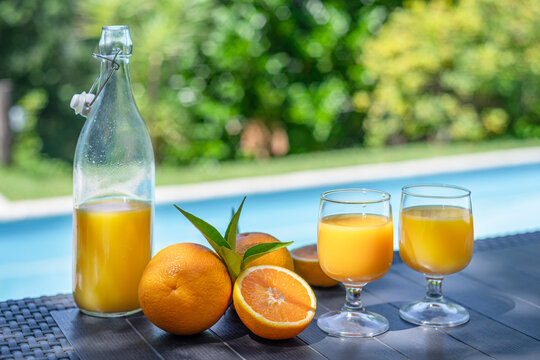 Pitcher and glasses of fresh orange juice with whole oranges.