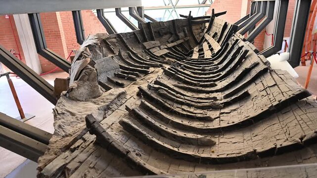ERCOLANO, ITALY - SEPTEMBER 26, 2026: Wooden remains of the ancient Roman boat preserved inside the Boat Pavilion at Herculaneum archaeological site.