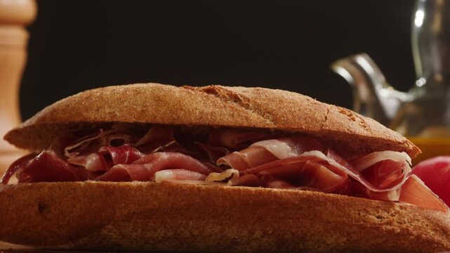 Sandwich with jamon serrano and iberico, Spanish cured ham bocadillo in crusty baguette, traditional prosciutto ham sandwich close up for breakfast in cafe