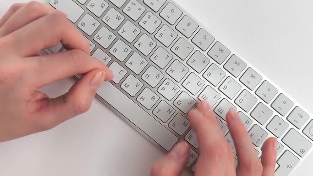 Copywriting process on a desktop computer keyboard viewed from a top down angle. Author drafts an online article or blog post during a remote freelance assignment. White workplace setting