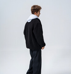 A young Asian man is wearing a black Sherpa fleece jacket, with a light gray hooded sweater underneath. © jeson