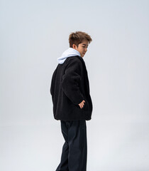 A young Asian man is wearing a black Sherpa fleece jacket, with a light gray hooded sweater underneath. © jeson