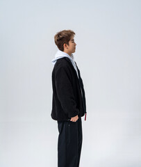 A young Asian man is wearing a black Sherpa fleece jacket, with a light gray hooded sweater underneath. © jeson