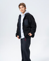 A young Asian man is wearing a black Sherpa fleece jacket, with a light gray hooded sweater underneath. © jeson