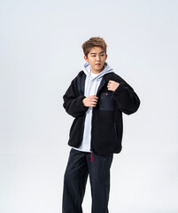 A young Asian man is wearing a black Sherpa fleece jacket, with a light gray hooded sweater underneath. © jeson