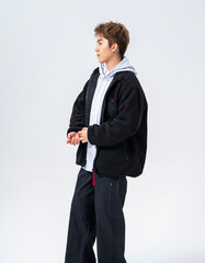 A young Asian man is wearing a black Sherpa fleece jacket, with a light gray hooded sweater underneath. © jeson