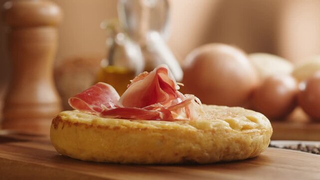 Spanish omelette with jamon serrano, tortilla and iberico cured ham appetizer on wooden table, traditional Spanish breakfast close up in cafe