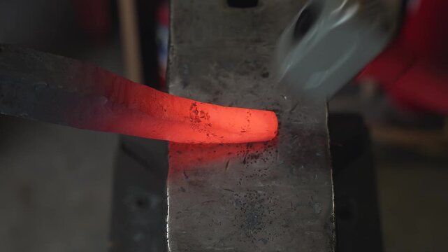 A blacksmith in the workshop takes out a red-hot spearhead (or sword blade) and hammers it while the heat lasts.