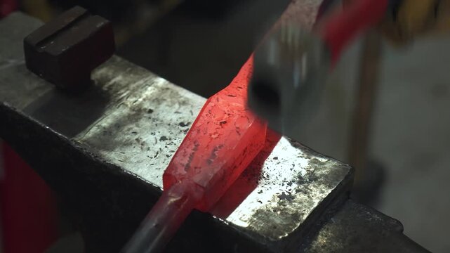 A blacksmith in the workshop takes out a red-hot spearhead (or sword blade) and hammers it while the heat lasts.