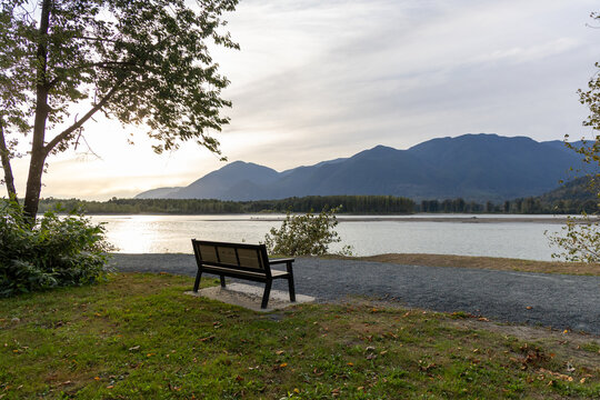 Empty Park Bench Overlooking River and Mountains at Island 22 Regional Park, Chilliwack, BC Canada