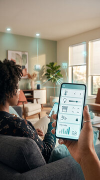 Asian man controlling smart home functions from a mobile phone while standing in a bright contemporary apartment, connected devices, wireless technology, IoT network, smart lighting, climate control, 