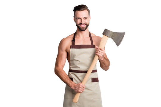 Portrait of attractive fit cheerful guy wearing apron holding in hand ax cut tool isolated over light grey pastel color background