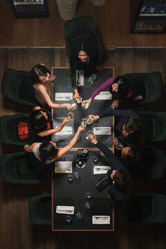 Group of diverse people, six friends having a nice time together, enjoying dining at a luxury modern restaurant, top down view.