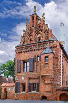Facade of the House of Perkunas in Kaunas, Lithuania. Gothic brick architecture under a partly cloudy sky