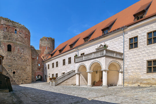 Courtyard view of Bauska Castle in Latvia with stairs and a high porch. Medieval architecture under a clear blue sky